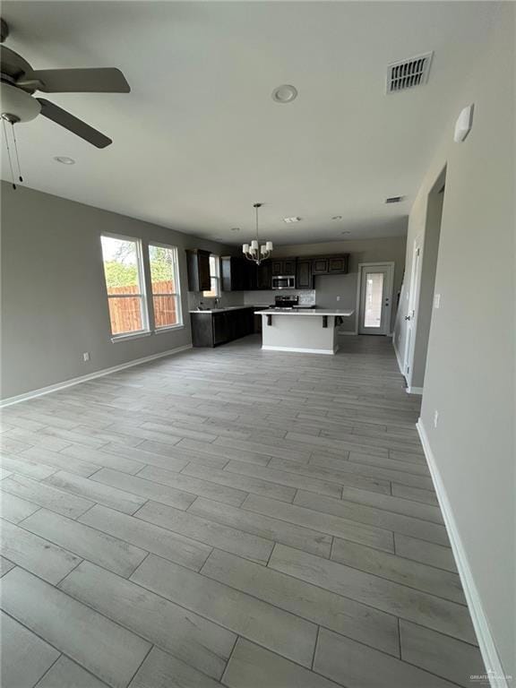 Unfurnished living room featuring a chandelier, light wood-style flooring, a ceiling fan, and recessed lighting