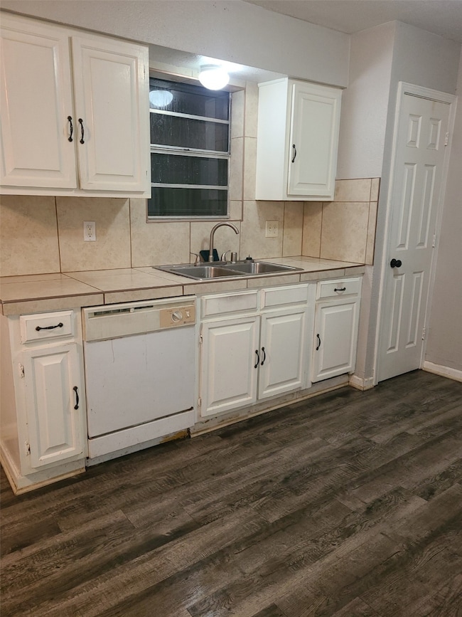 Kitchen featuring dishwasher, dark wood-type flooring, white cabinetry, and decorative backsplash