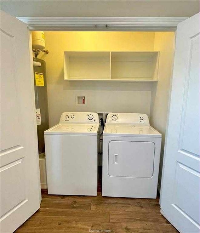 Laundry area with dark wood finished floors, independent washer and dryer, and water heater