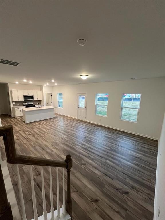 Unfurnished living room with dark wood-style floors and recessed lighting