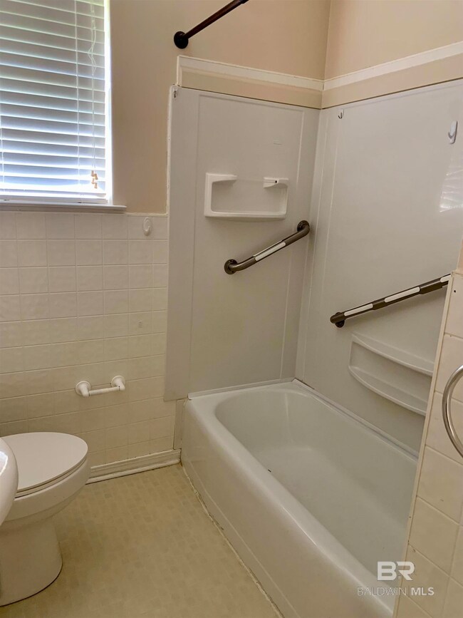 Bathroom with toilet, shower / tub combination, and tile patterned flooring