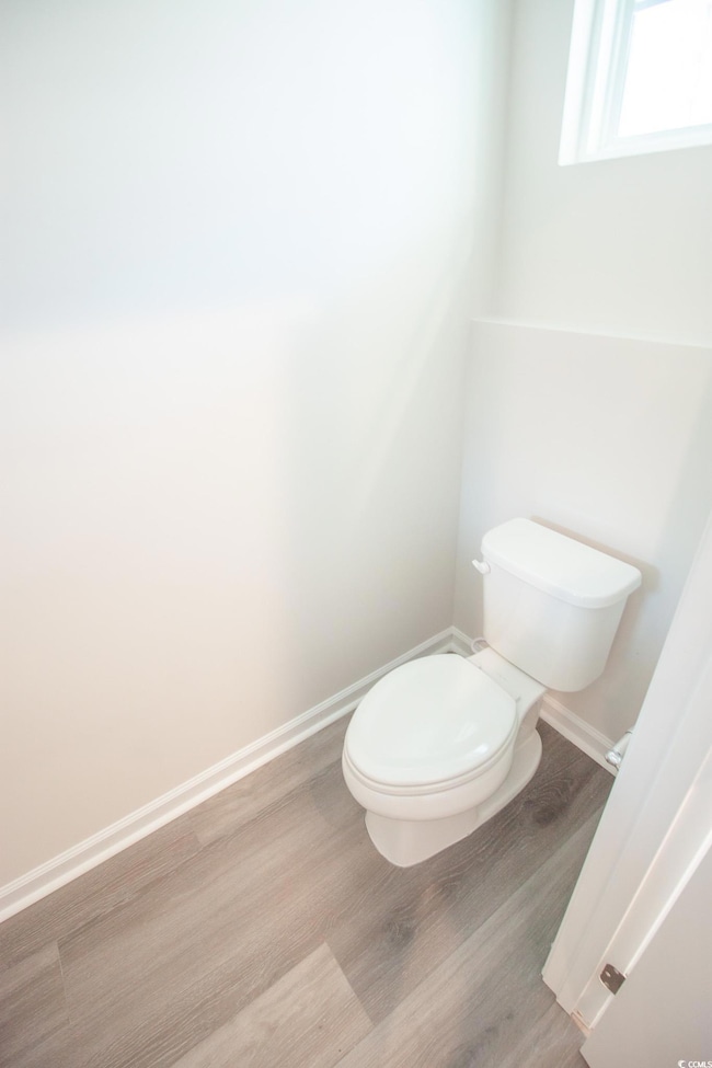 Bathroom with toilet, wood finished floors, and baseboards