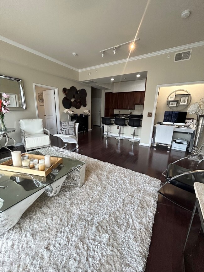 Living area featuring ornamental molding, rail lighting, and dark wood-style floors