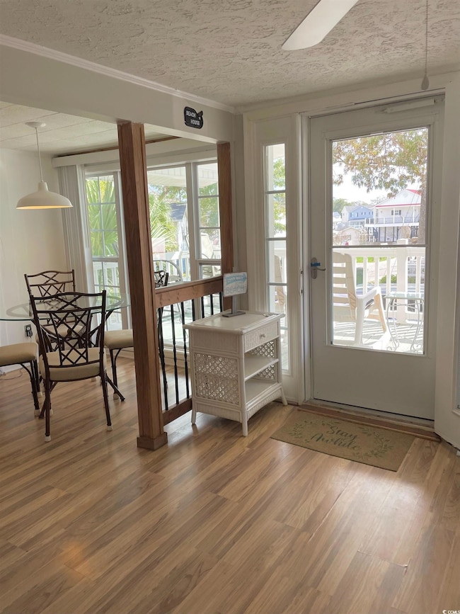 Doorway to outside with wood finished floors, plenty of natural light, and ornamental molding