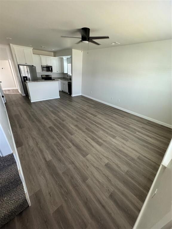 Unfurnished living room featuring baseboards, a ce