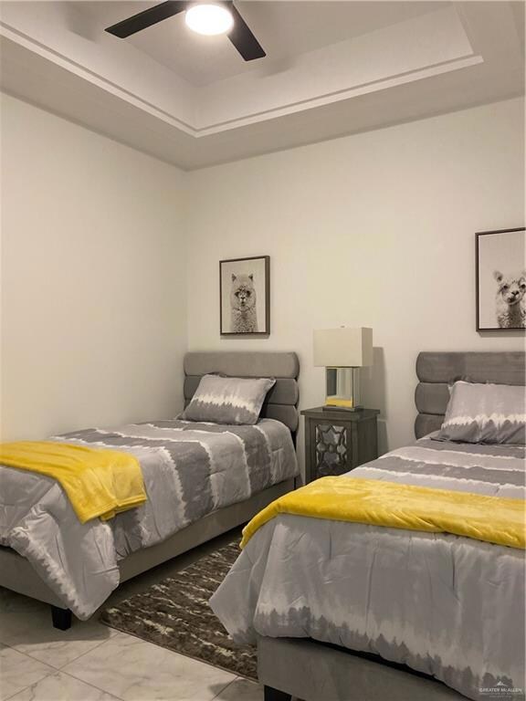 Tiled bedroom with a raised ceiling and ceiling fan