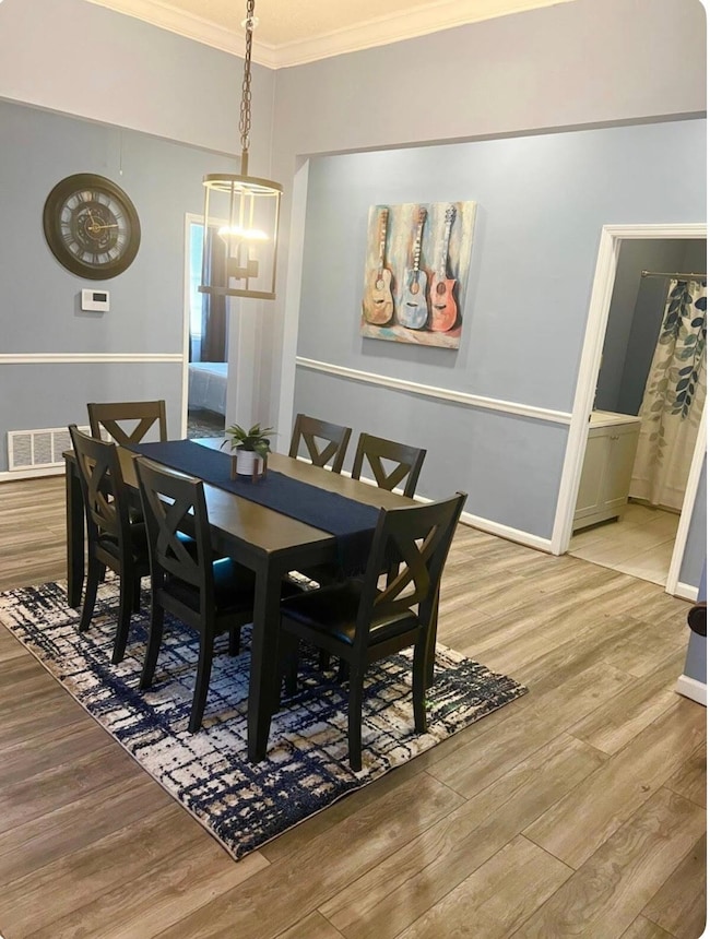 Dining area with ornamental molding, wood finished floors, a chandelier, and baseboards