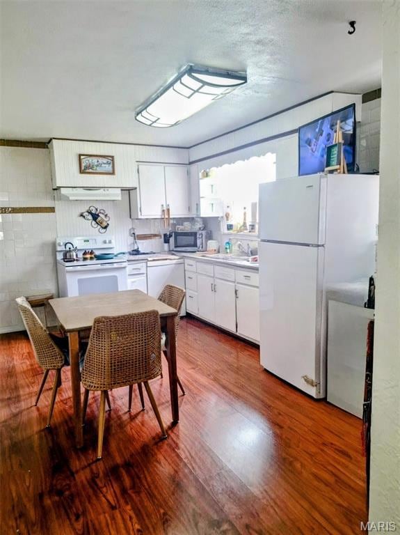 Kitchen featuring white cabinets, white appliances, light countertops, wood finished floors, and a textured ceiling