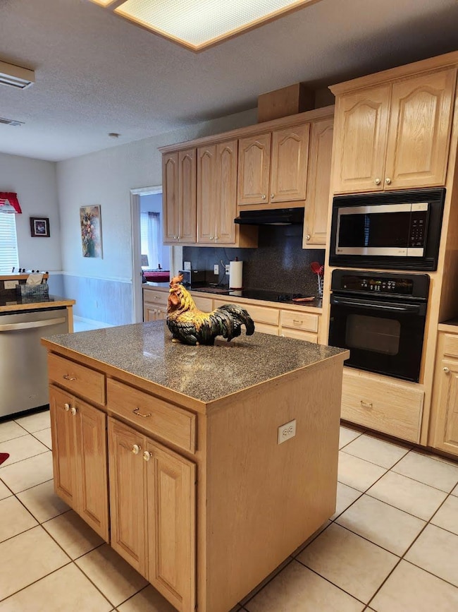 Kitchen with black appliances, light brown cabine
