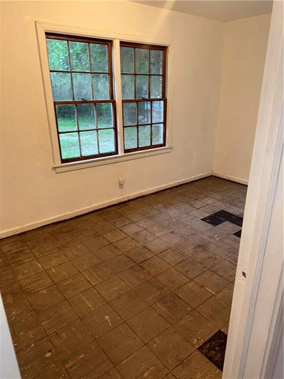 Empty room with baseboards and brick patterned floors
