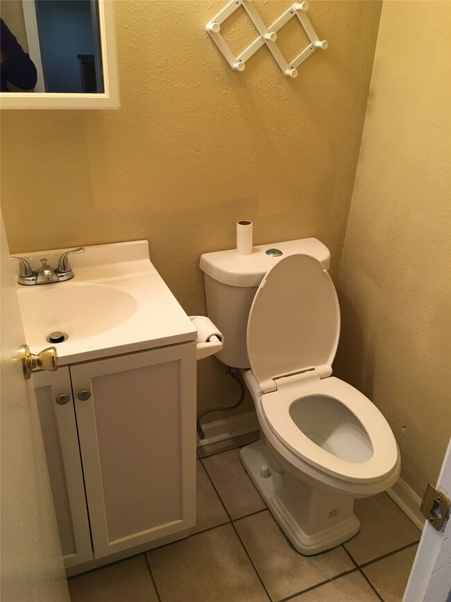 Half bathroom featuring a textured wall, light tile patterned floors, and vanity