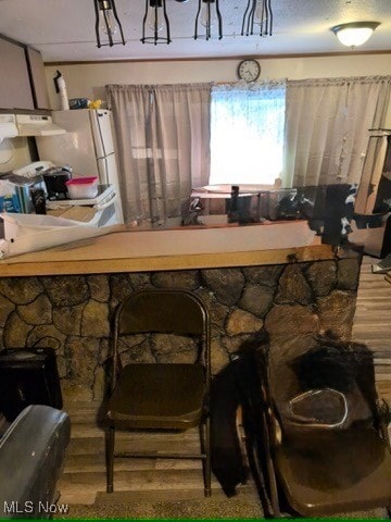 Bar area featuring wood finished floors, under cabinet range hood, and stove