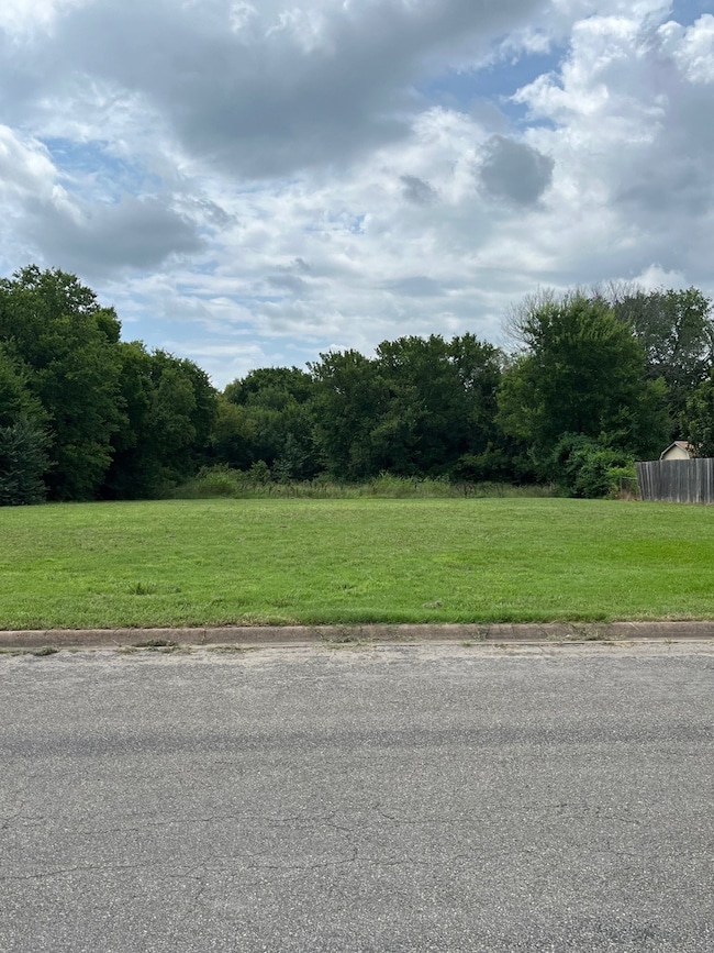View of asphalt road featuring curbs and a view of trees