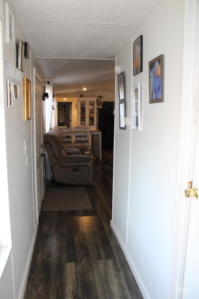 Corridor with dark wood finished floors and a textured ceiling