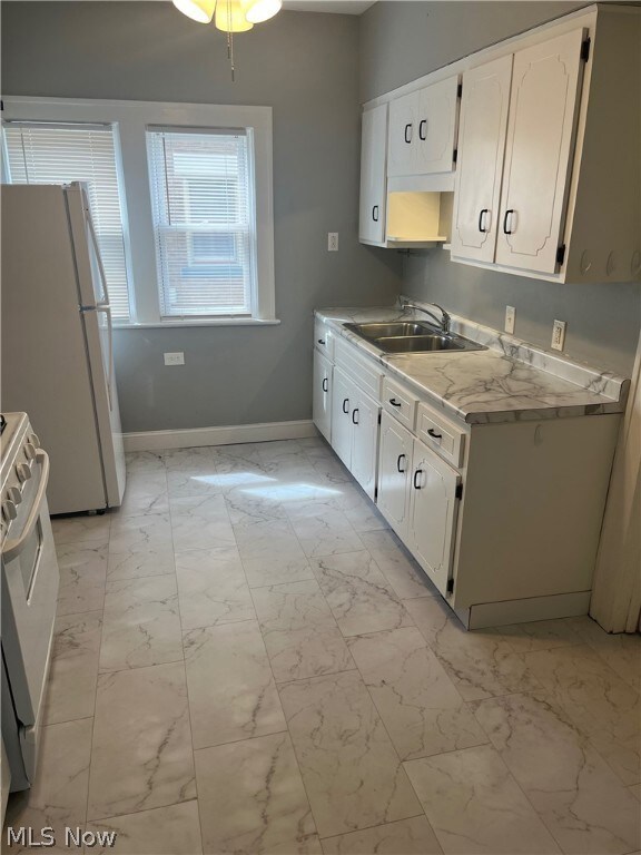 Kitchen with white appliances, white cabinetry, sink, and light tile flooring