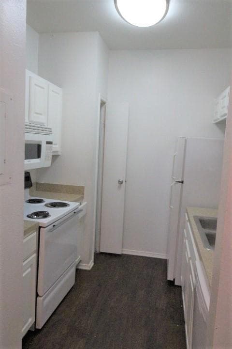 Kitchen featuring white appliances, white cabinetry, and light countertops