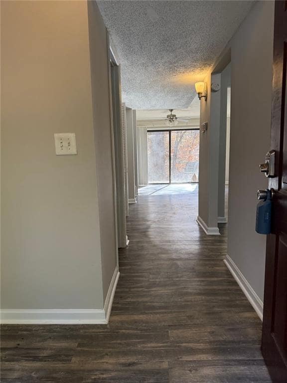Hallway with dark wood-type flooring and a textured ceiling