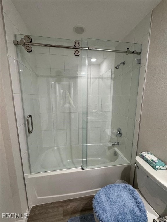 Bathroom with bath / shower combo with glass door, wood finished floors, and a textured wall