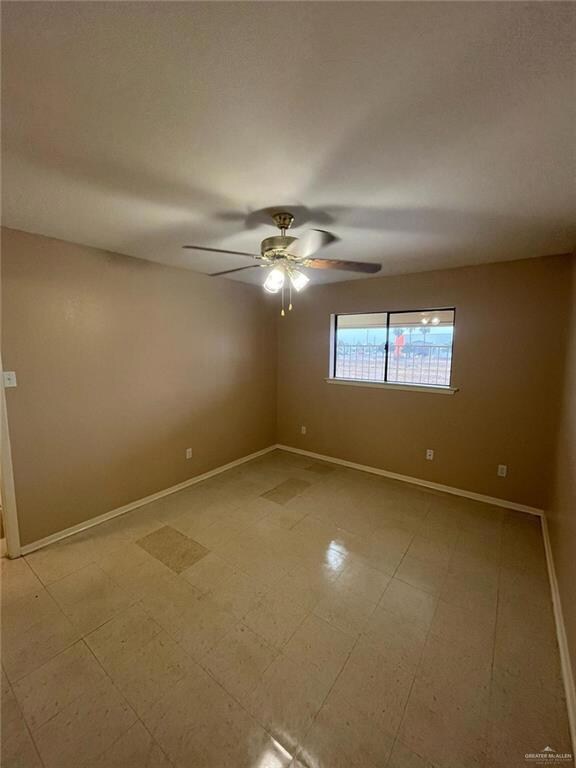 Empty room featuring ceiling fan, light floors, and baseboards
