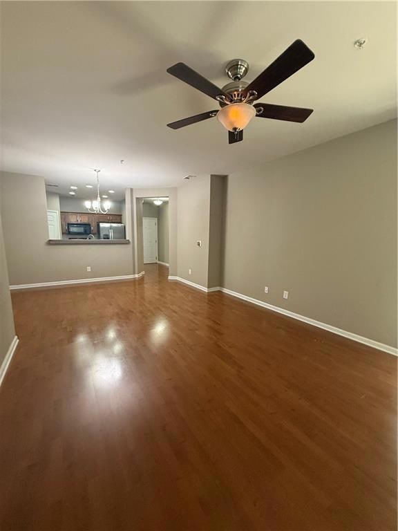 Unfurnished living room with a chandelier and dark wood-style floors