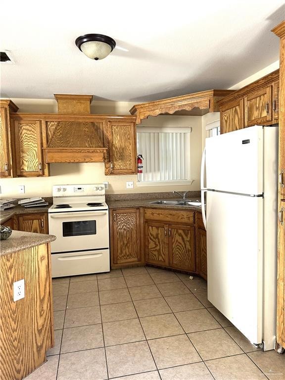 Kitchen featuring white appliances, light tile patterned floors, and brown cabinets