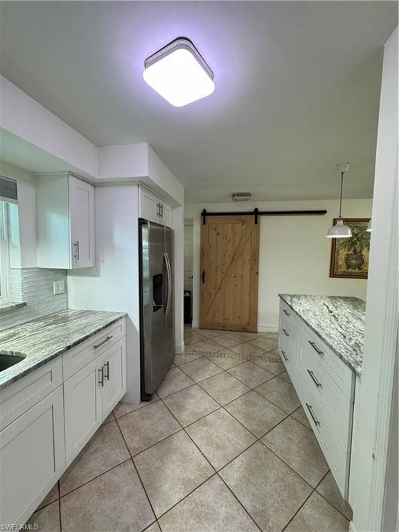 Kitchen featuring white cabinetry, a barn door, ha