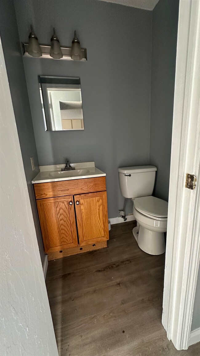 Half bath with baseboards, wood finished floors, t