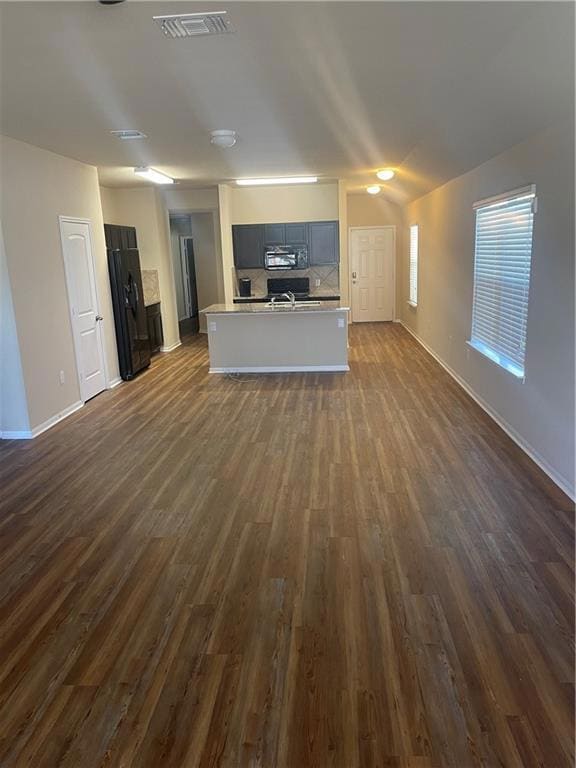 Unfurnished living room with dark wood-style floo