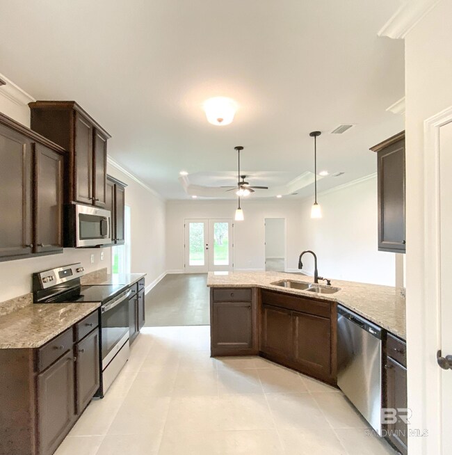 Kitchen with appliances with stainless steel finishes, light tile patterned flooring, ceiling fan, and sink