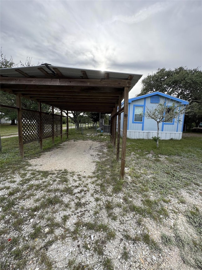 View of car parking with dirt driveway and a carp