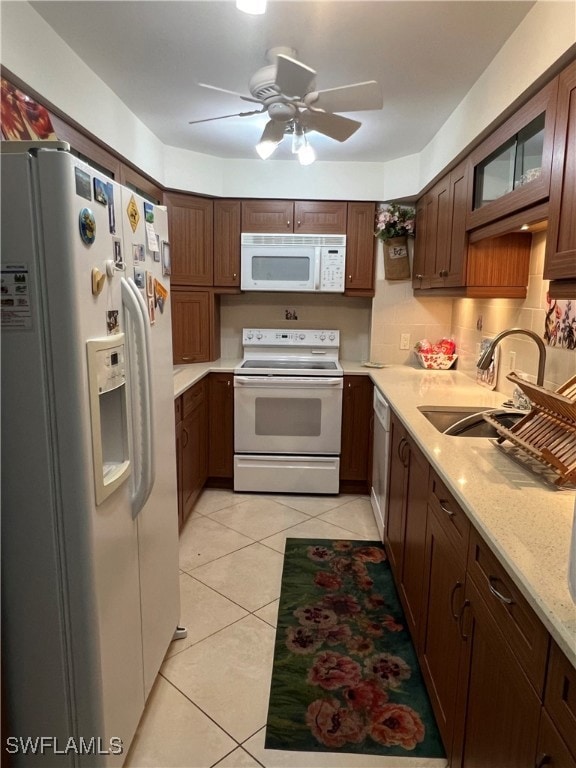 Kitchen with ceiling fan, white appliances, backsplash, light tile floors, and sink