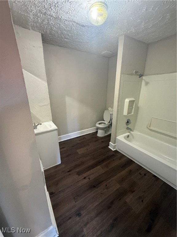 Bathroom featuring vanity, tub / shower combination, dark wood finished floors, and a textured ceiling