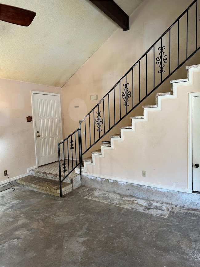 Stairway with a textured ceiling and lofted ceilin