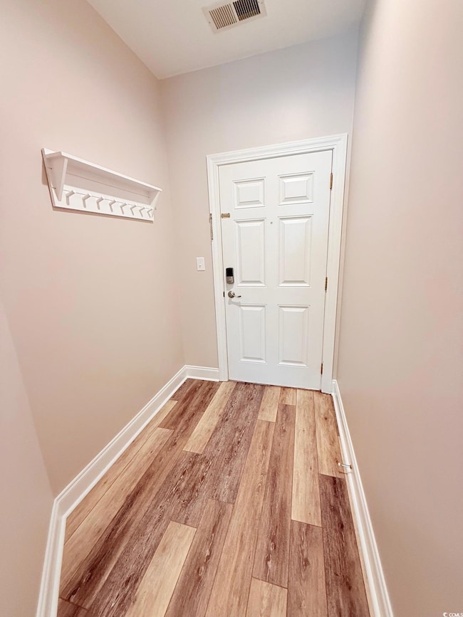 Entryway with light wood-style flooring, visible vents, and baseboards