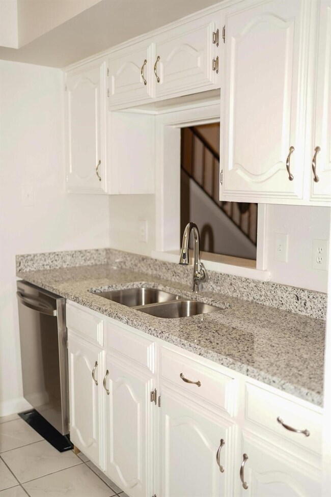 Kitchen featuring dishwasher, a sink, and white ca