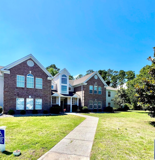 Traditional-style home with a front yard and brick