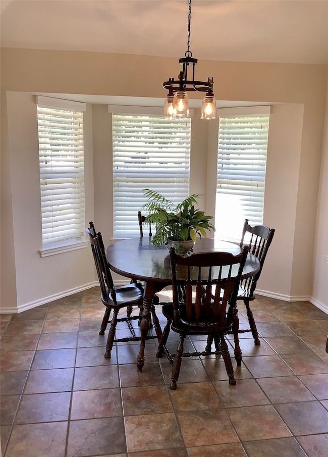 Dining space featuring healthy amount of natural light, a chandelier, and dark tile patterned flooring