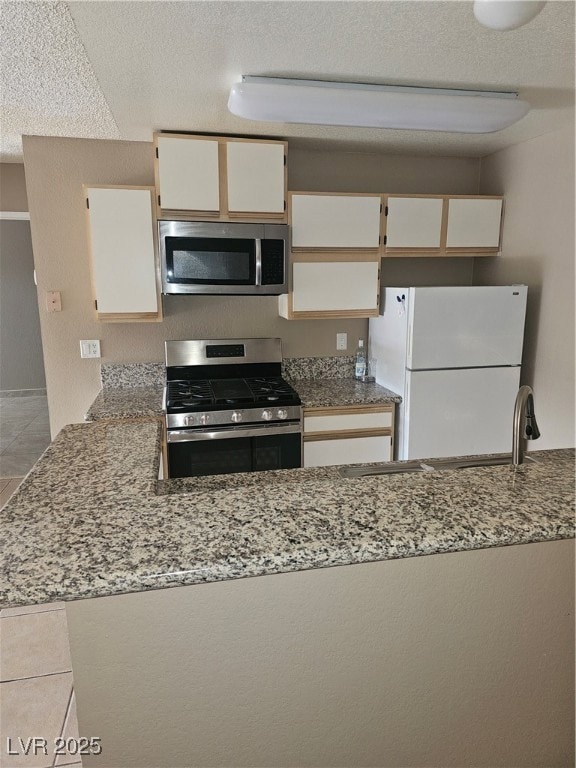 Kitchen featuring a sink, range, fridge, and stone