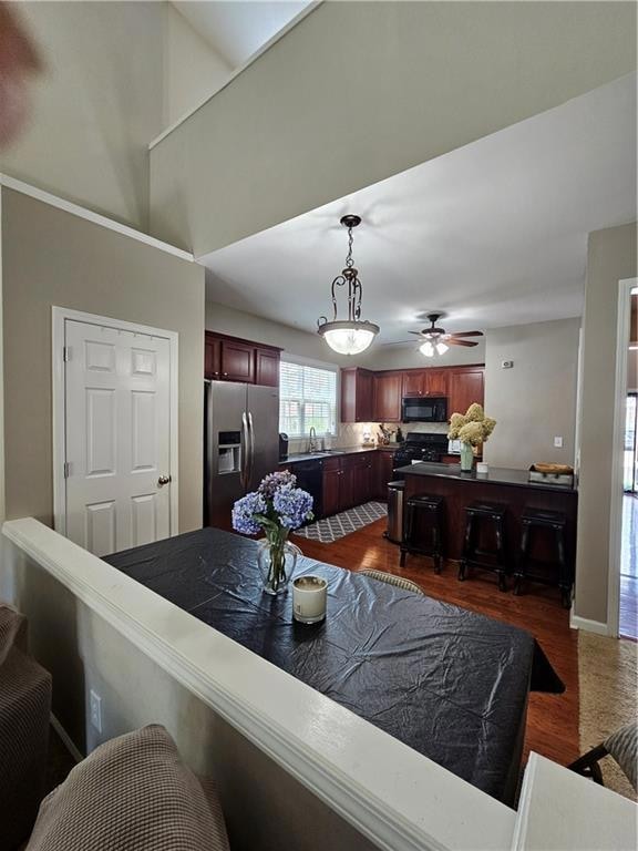 Kitchen featuring fridge, range, dark wood-type flooring, pendant lighting, and a breakfast bar
