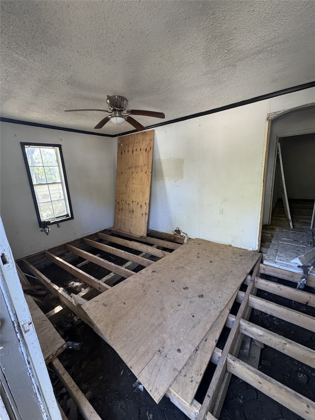 Empty room with a ceiling fan and a textured ceiling