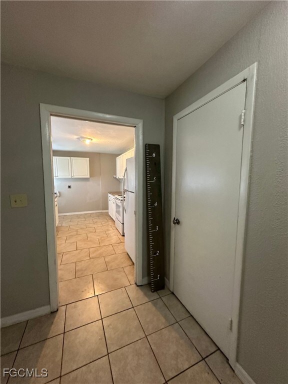 Kitchen featuring white cabinetry, light tile patterned flooring, white appliances, and light countertops