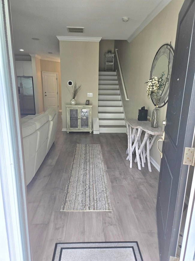 Foyer with crown molding, stairway, baseboards, an
