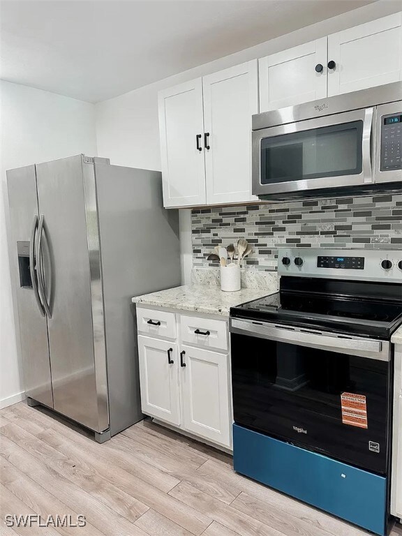 Kitchen with stainless steel appliances, light woo