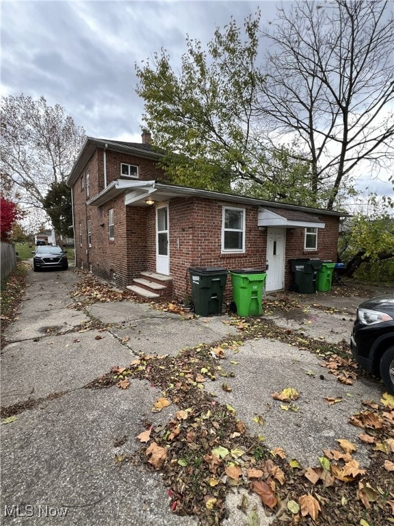 Back of house featuring brick siding and a chimney