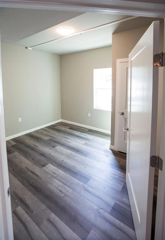 Spare room with baseboards and dark wood-style floors