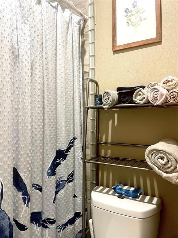 Bathroom with toilet and a shower with curtain