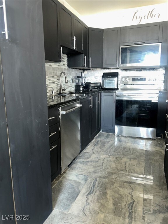 Kitchen with dark stone countertops, a sink, dishw