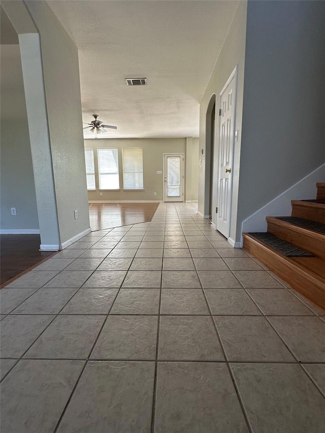 Empty room with a ceiling fan, tile patterned flo
