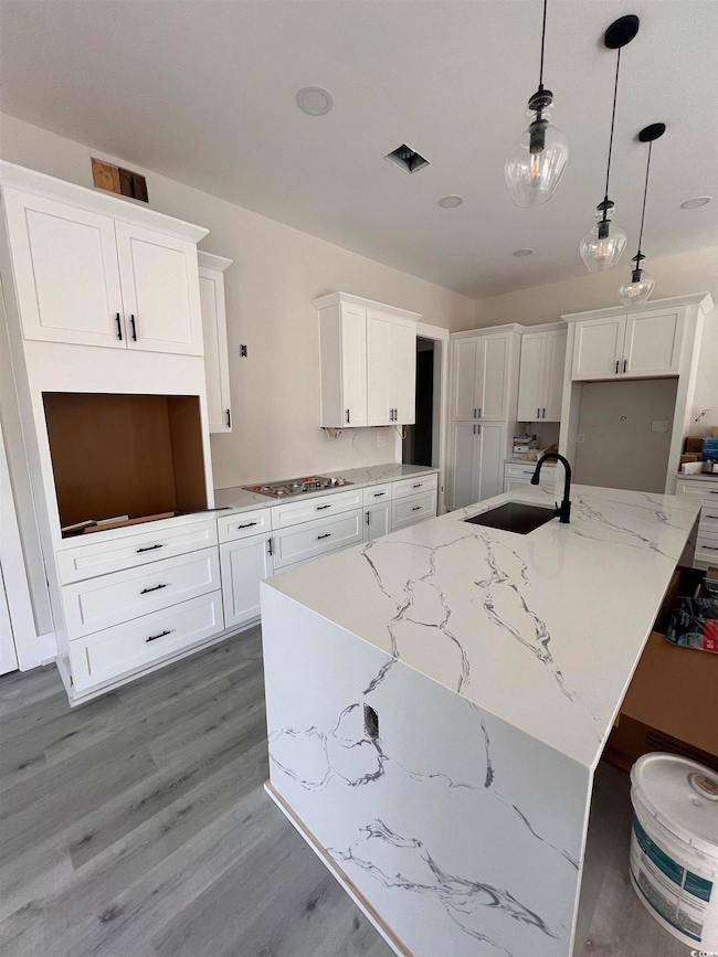 Kitchen featuring a center island with sink, a sin