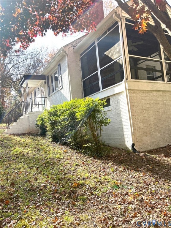 View of property exterior with a sunroom and brick siding